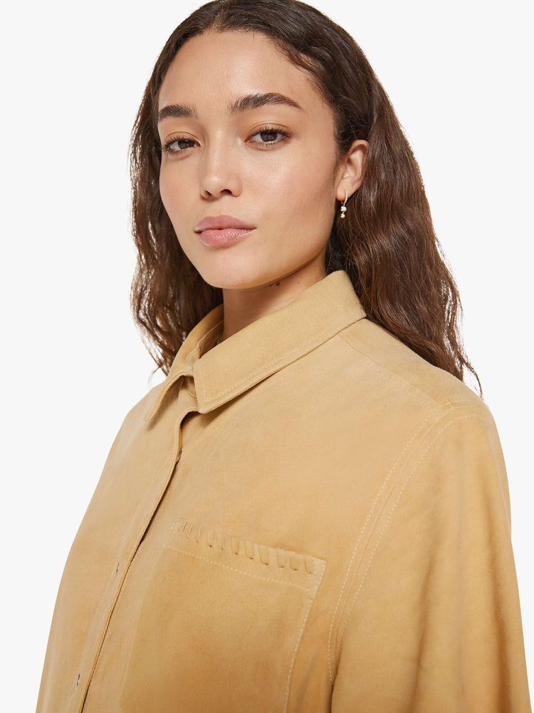 Close up view of a woman in a light khaki button up dress with a collared neck, short sleeves and a boxy fit.