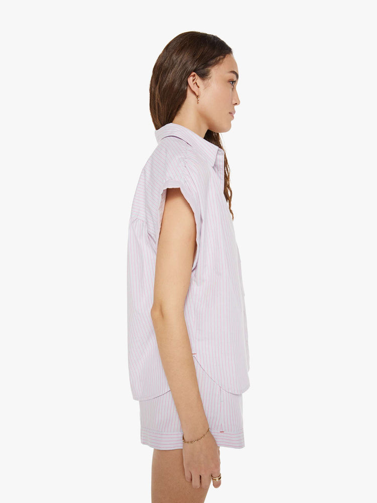 Side view of a woman in a pink and grey stripe sleeveless button-down shirt.
