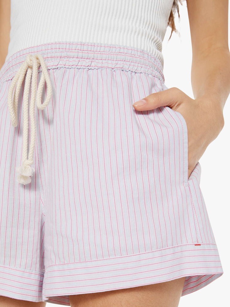 Close up view of a woman in pink and grey shorts with an elastic drawstring waist, slit pockets and a loose fit.