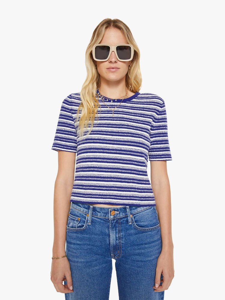 Front view of a woman in a white with blue horizontal stripe short-sleeved crewneck tee.