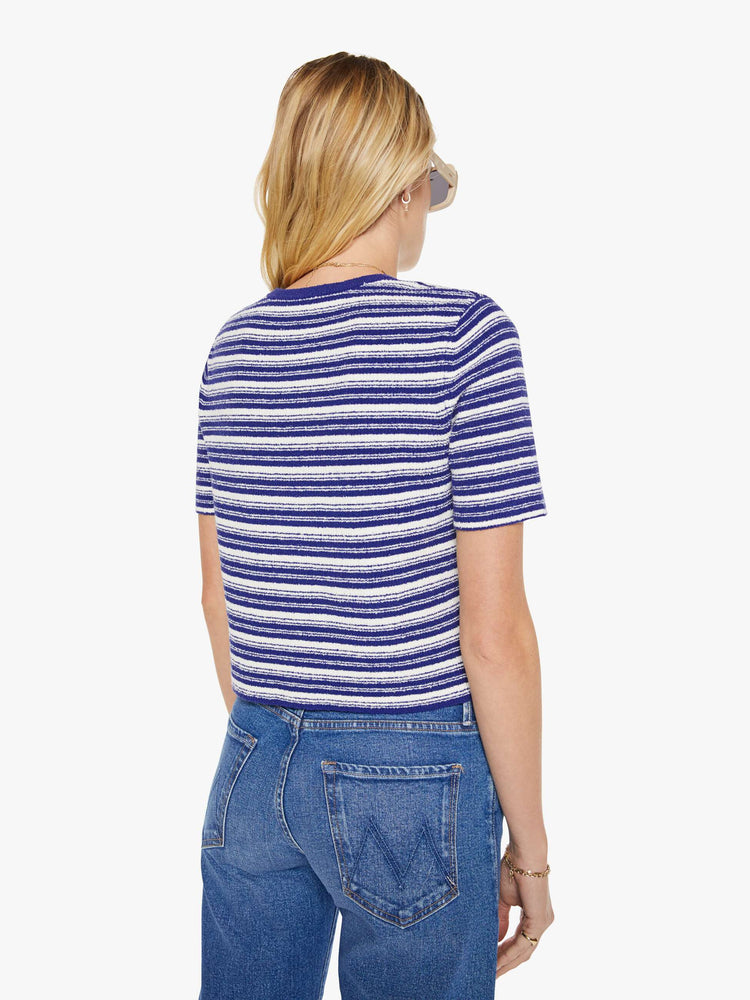 Back view of a woman in a white with blue horizontal stripe short-sleeved crewneck tee.