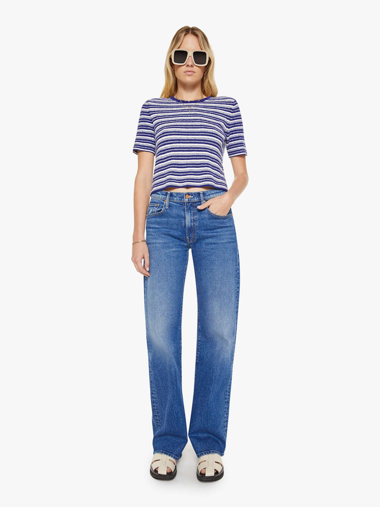 Full body view of a woman in a white with blue horizontal stripe short-sleeved crewneck tee.