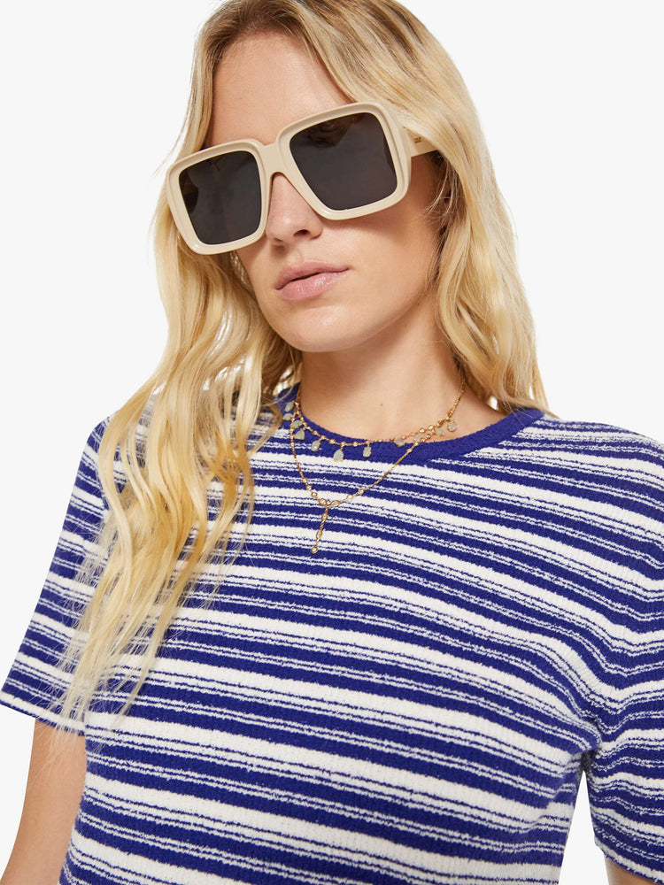 Close up view of a woman in a white with blue horizontal stripe short-sleeved crewneck tee.