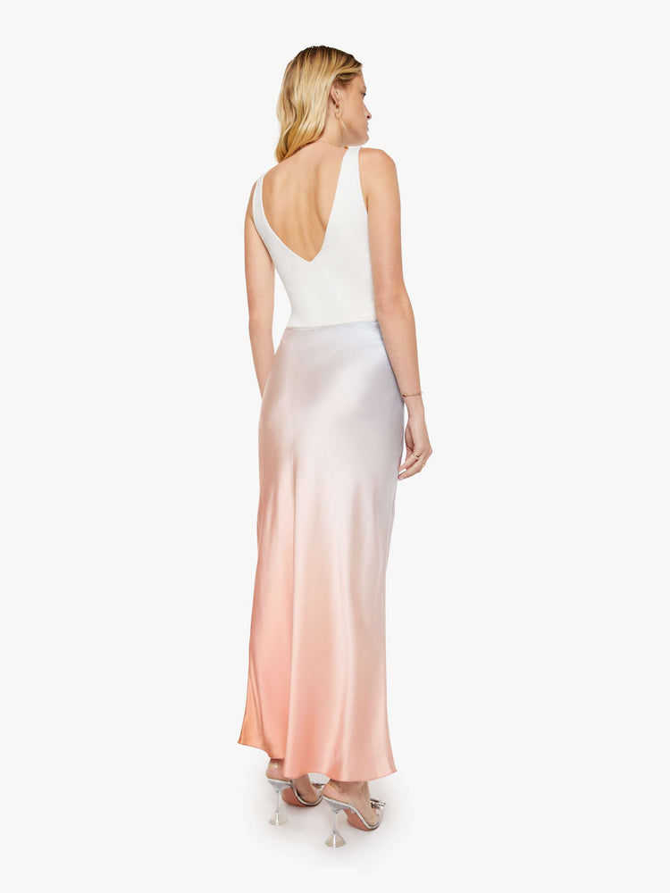 Back view of a woman in a sky blue and melon pink ombre bias cut maxi skirt is designed with a straight fit and a flowy ankle-grazing hem.