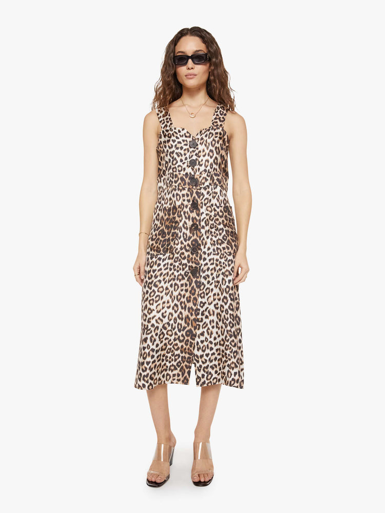 Front view of a woman in a cheetah print dress and features wide straps, a scoop neck, black buttons down the front and a calf-length hem.