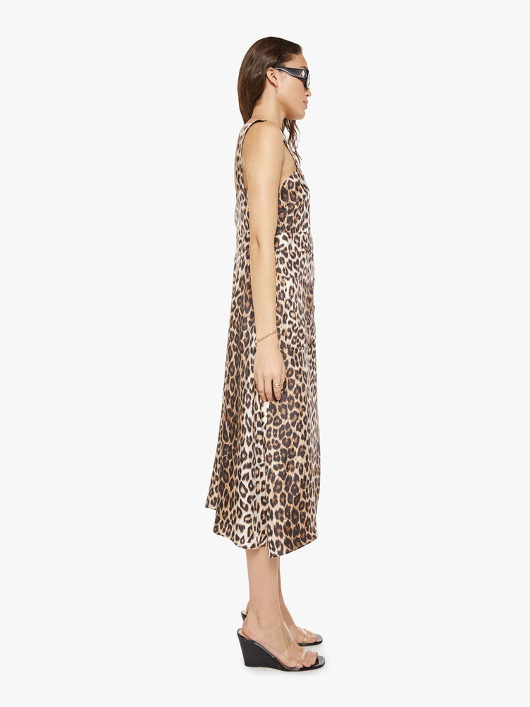 Side view of a woman in a cheetah print dress and features wide straps, a scoop neck, black buttons down the front and a calf-length hem.