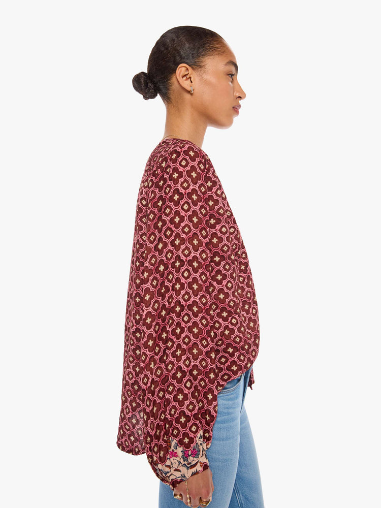 Side view of a woman in a brick red mosaic print with a crew neck, long balloon sleeves and ruffles throughout for a flowy fit.