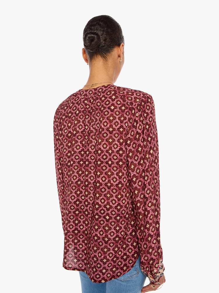 Back view of a woman in a brick red mosaic print with a crew neck, long balloon sleeves and ruffles throughout for a flowy fit.