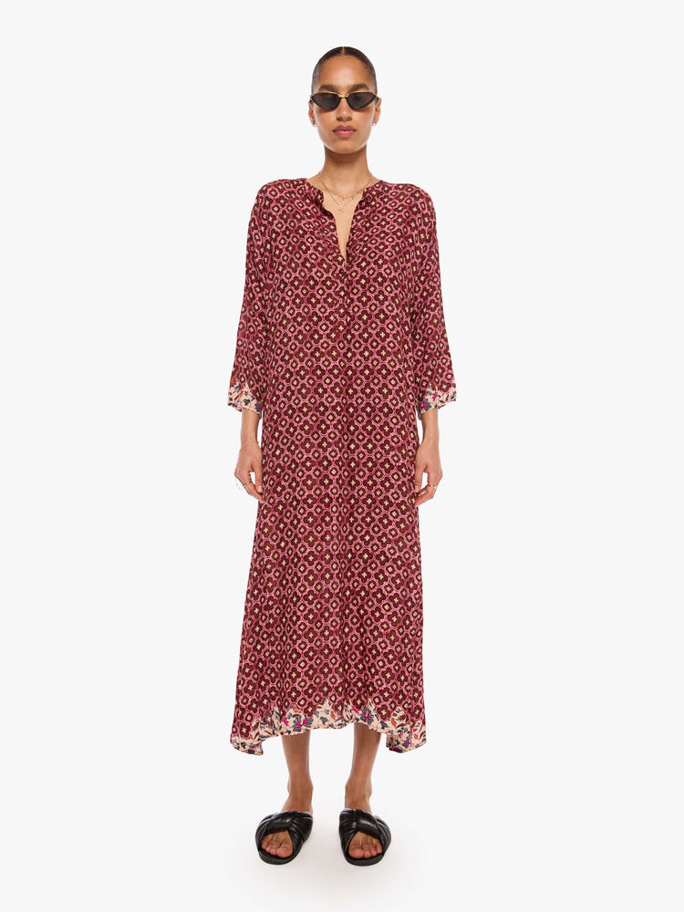 Front view of a woman in a brick red mosaic print flowy dress is designed with a deep V-neck, 3/4 sleeves and thigh-high side slits.
