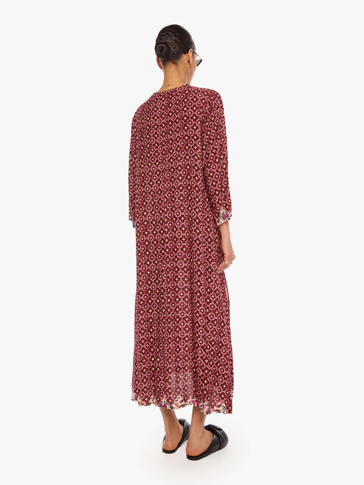 Back view of a woman in a brick red mosaic print flowy dress is designed with a deep V-neck, 3/4 sleeves and thigh-high side slits.