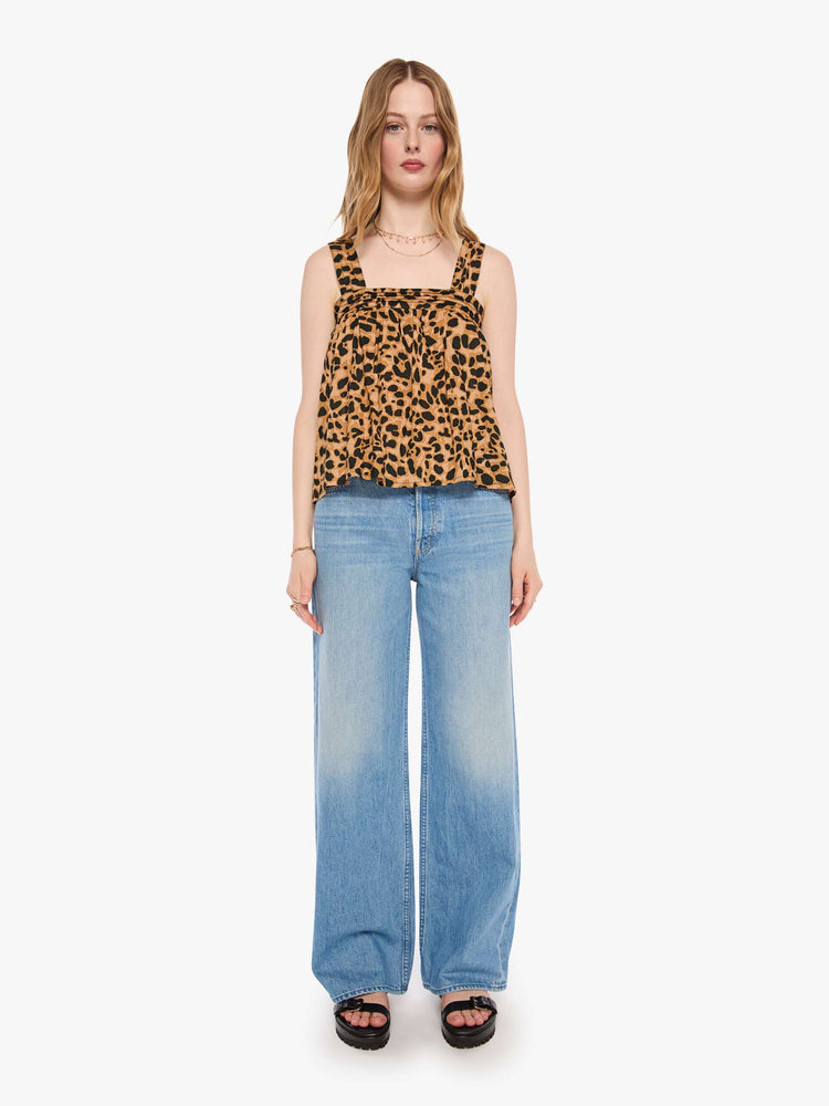 Full body view of a woman in a leopard top with detailed straps and buttons in the back.