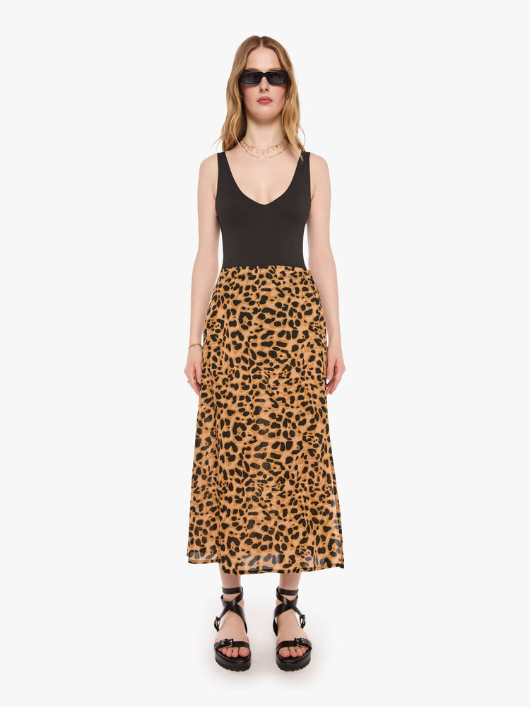 Front view of a woman in a leopard skirt with a high rise, calf-length hem and a loose, flowy fit.