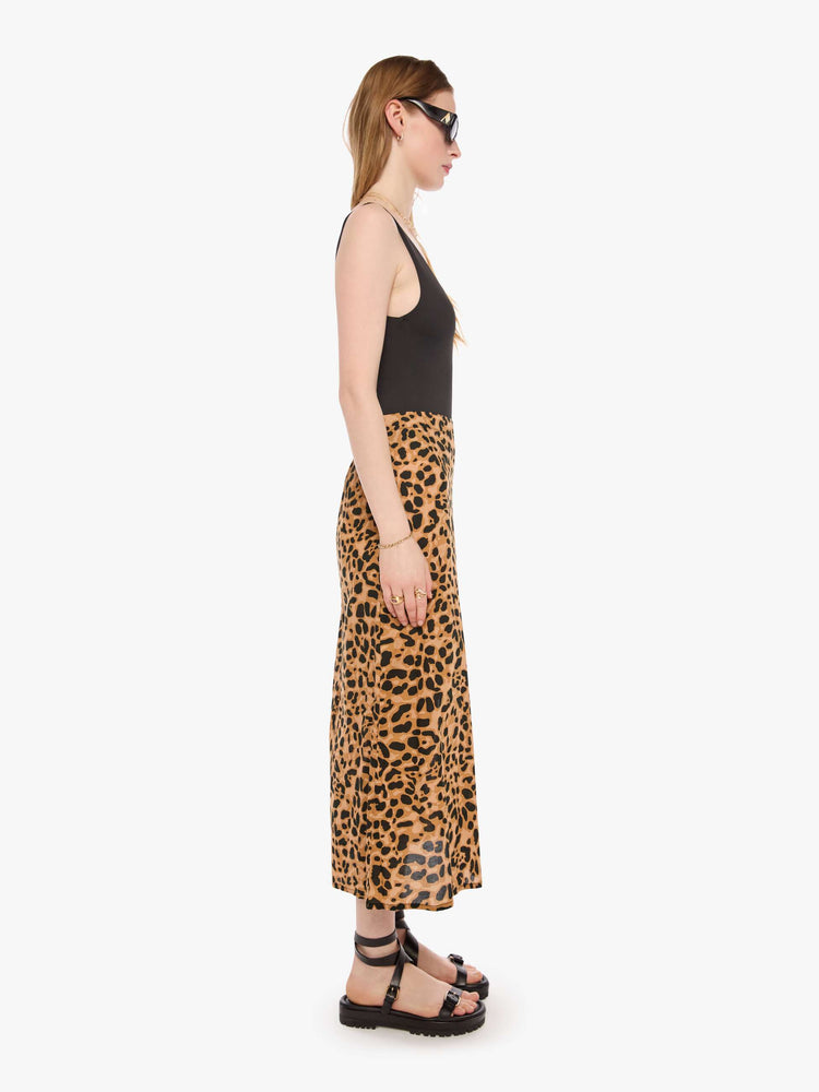 Side view of a woman in a leopard skirt with a high rise, calf-length hem and a loose, flowy fit.