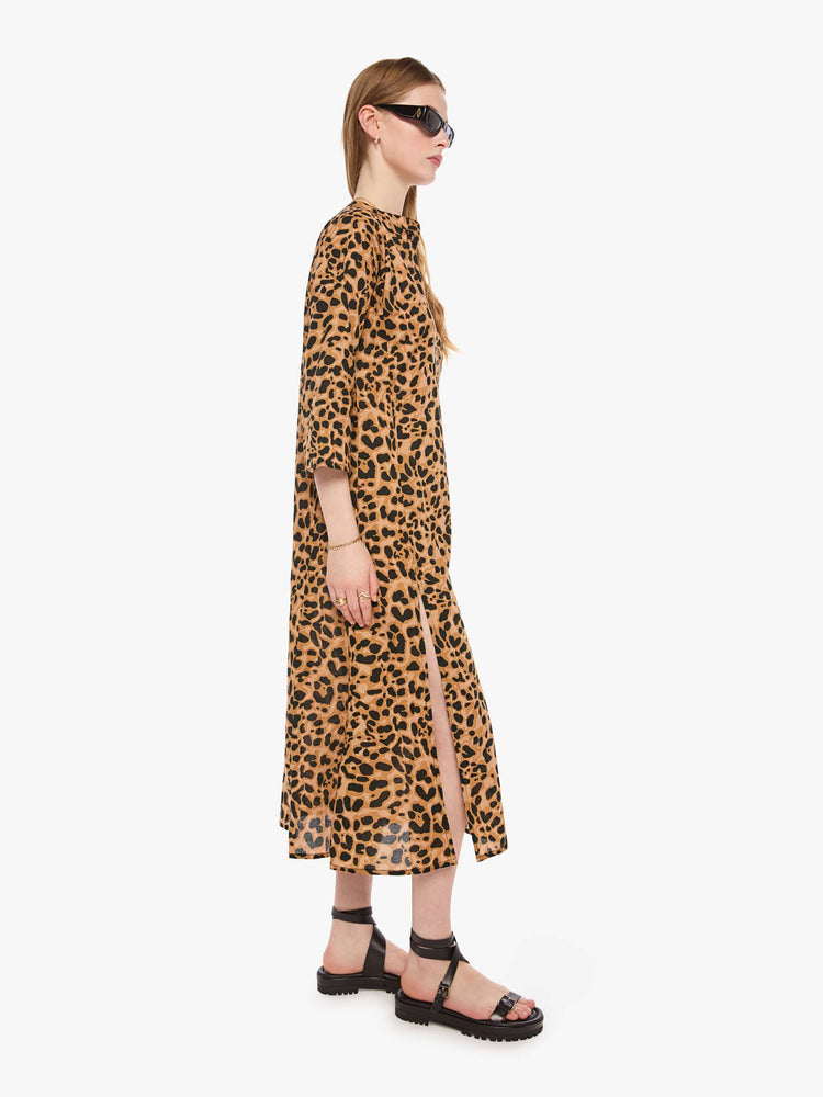Side view of a woman in a leopard print flowy dress with a deep V-neck, 3/4 sleeves and thigh-high side slits.