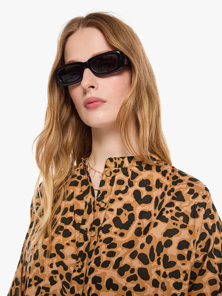 Close up view of a woman in a leopard print flowy dress with a deep V-neck, 3/4 sleeves and thigh-high side slits.