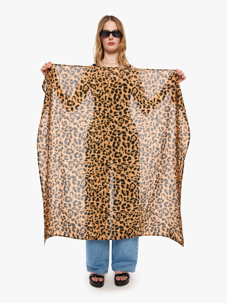 Front view of a woman holding a leopard print  square scarf.