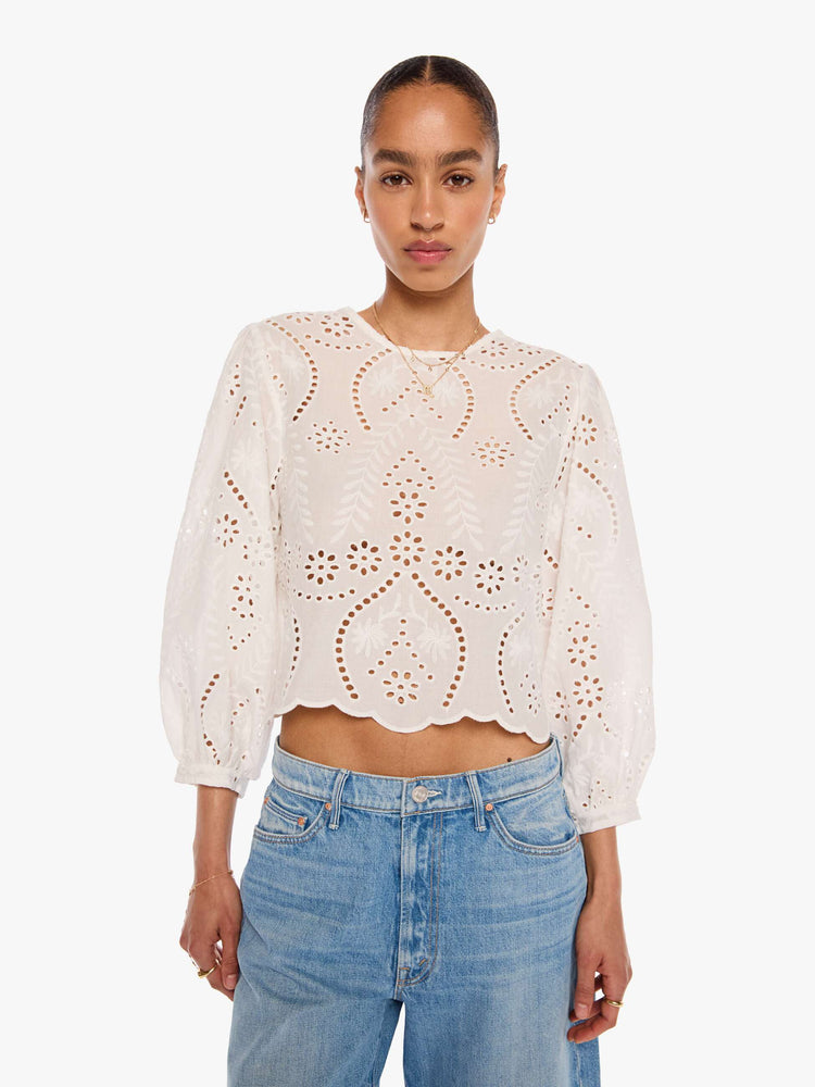Front view of a woman in a white top with embroidery and eyelet details, and features a crewneck, 3/4-length balloon sleeves, a slightly cropped scalloped hem and a boxy fit.