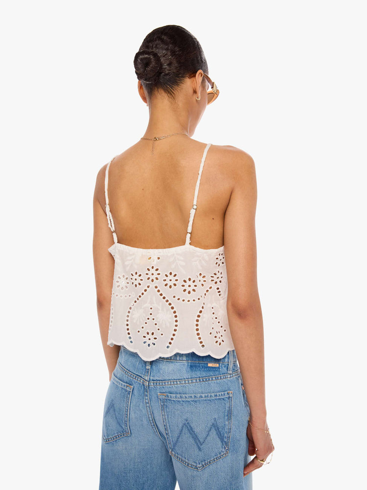 Back view of a woman in an off-white with delicate embroidery, eyelet details and a scalloped hem, the Fern cami has a square neck, spaghetti straps and a cropped, boxy fit.