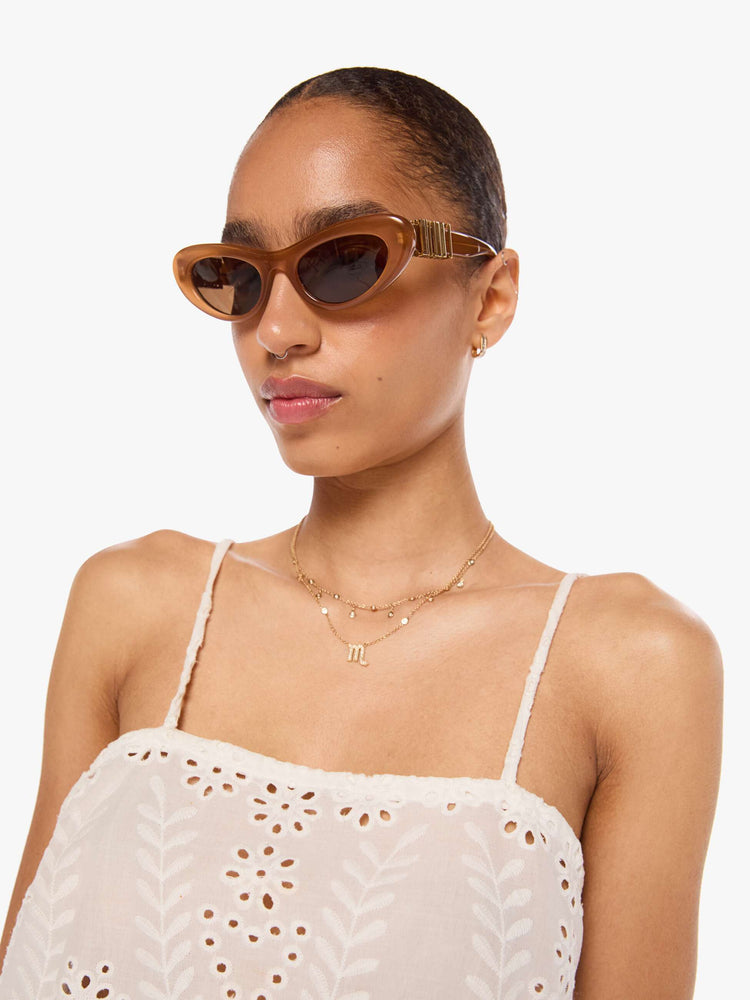 Close up view of a woman in an off-white with delicate embroidery, eyelet details and a scalloped hem, the Fern cami has a square neck, spaghetti straps and a cropped, boxy fit.