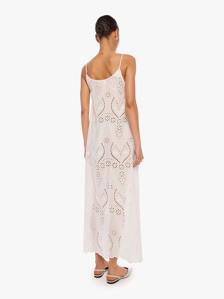 Back view of a woman in a dress with a scoop neck, thin spaghetti straps, an ankle-length hem and a loose, flowy fit.