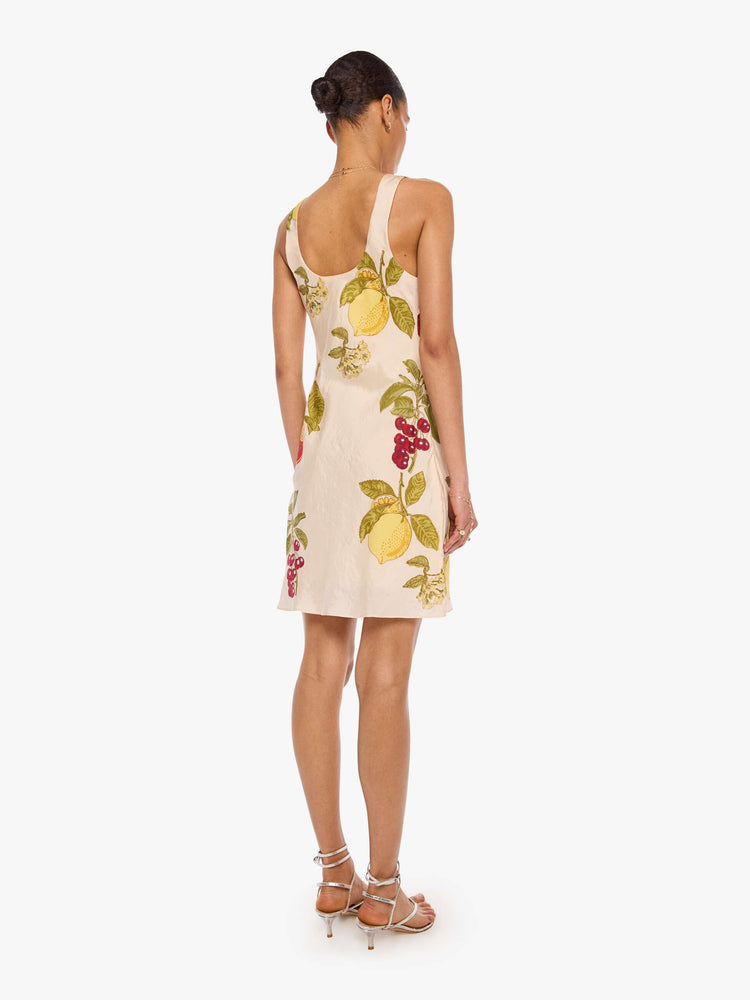 Back view of a woman in a  sleeveless Addie dress is made from 100% silk in cream with an oversized fruit print, and features a scoop neck, narrow fit and short hem.