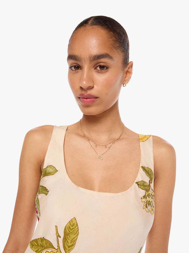 Close up view of a woman in a  sleeveless Addie dress is made from 100% silk in cream with an oversized fruit print, and features a scoop neck, narrow fit and short hem.