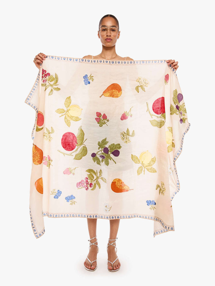 Model holding cream scarf with an oversized fruit print, and can be worn as a dress, top, skirt or accessory.