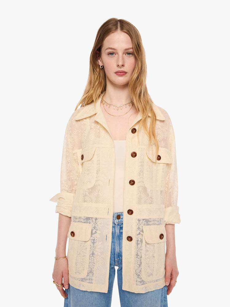 Front view of a woman in cream jacket with brown buttons, and features oversized patch pockets, 3/4-length sleeves, an extra-long hem and a boxy fit.
