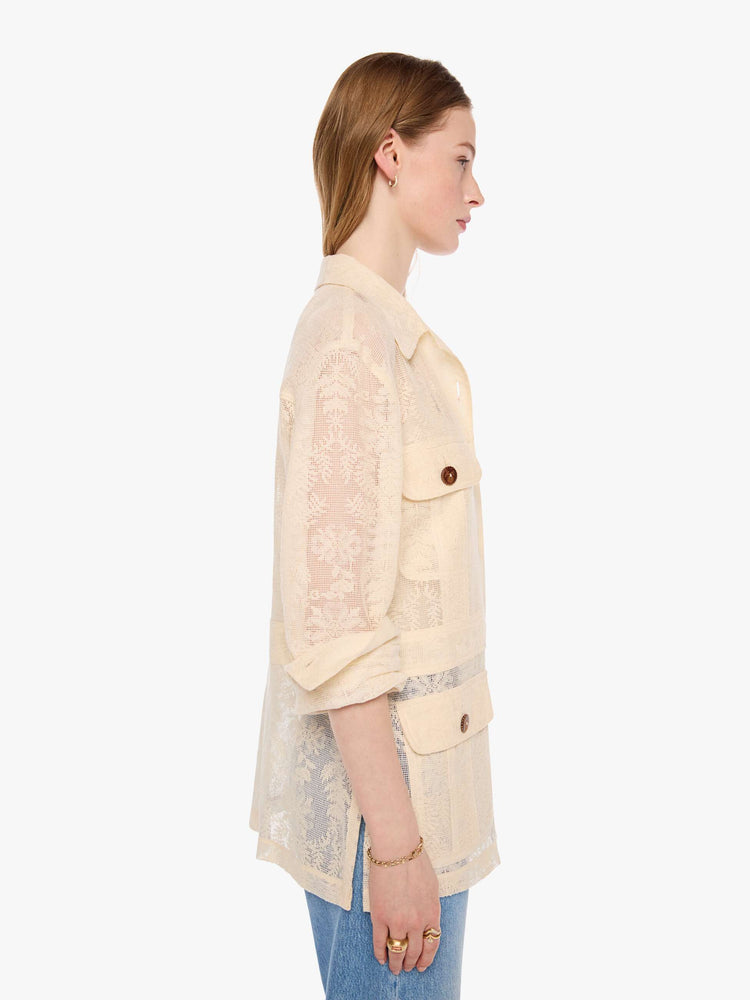 Side view of a woman in cream jacket with brown buttons, and features oversized patch pockets, 3/4-length sleeves, an extra-long hem and a boxy fit.