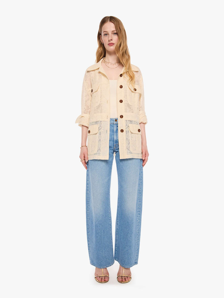 Full body view of a woman in cream jacket with brown buttons, and features oversized patch pockets, 3/4-length sleeves, an extra-long hem and a boxy fit.
