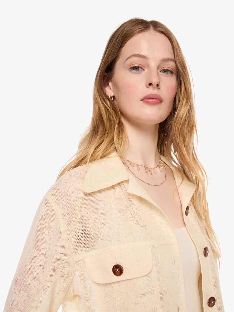Close up view of a woman in cream jacket with brown buttons, and features oversized patch pockets, 3/4-length sleeves, an extra-long hem and a boxy fit.