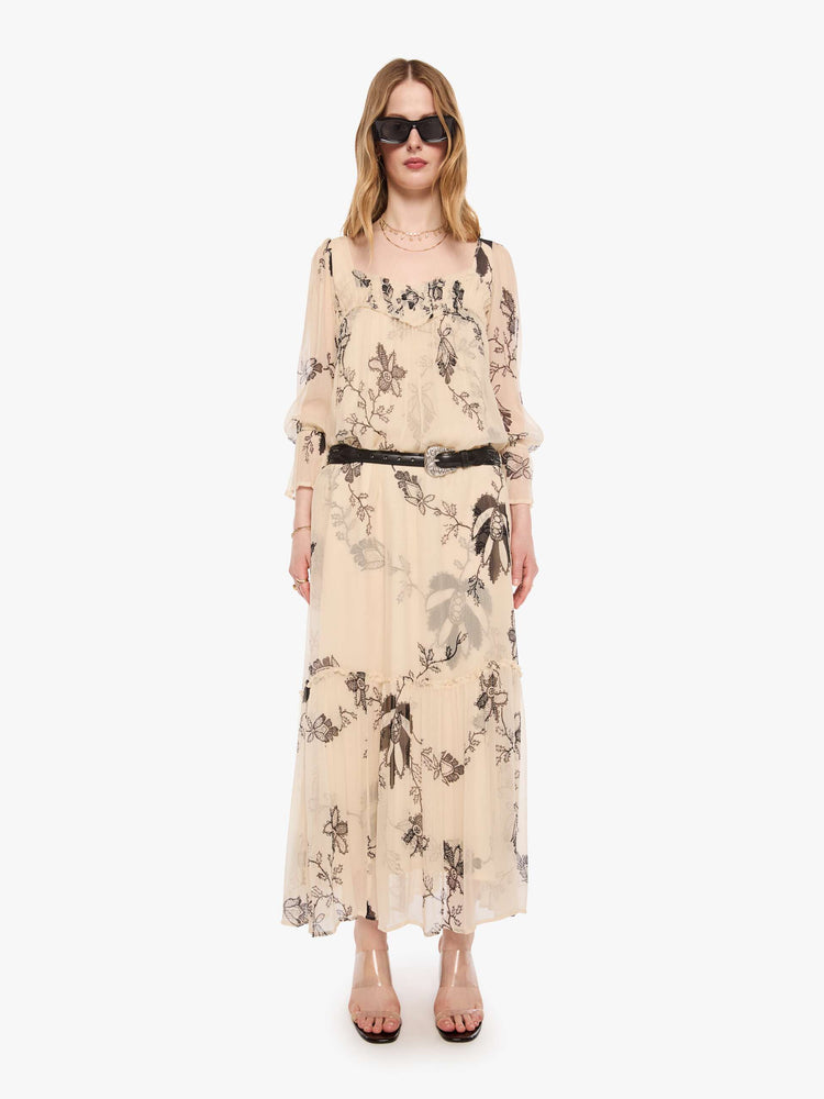 Front view of a woman in a lace printed chiffon overlay dress and features a rounded square neck, long balloon sleeves with elastic hems and a loose, flowy skirt with an ankle-length hem.