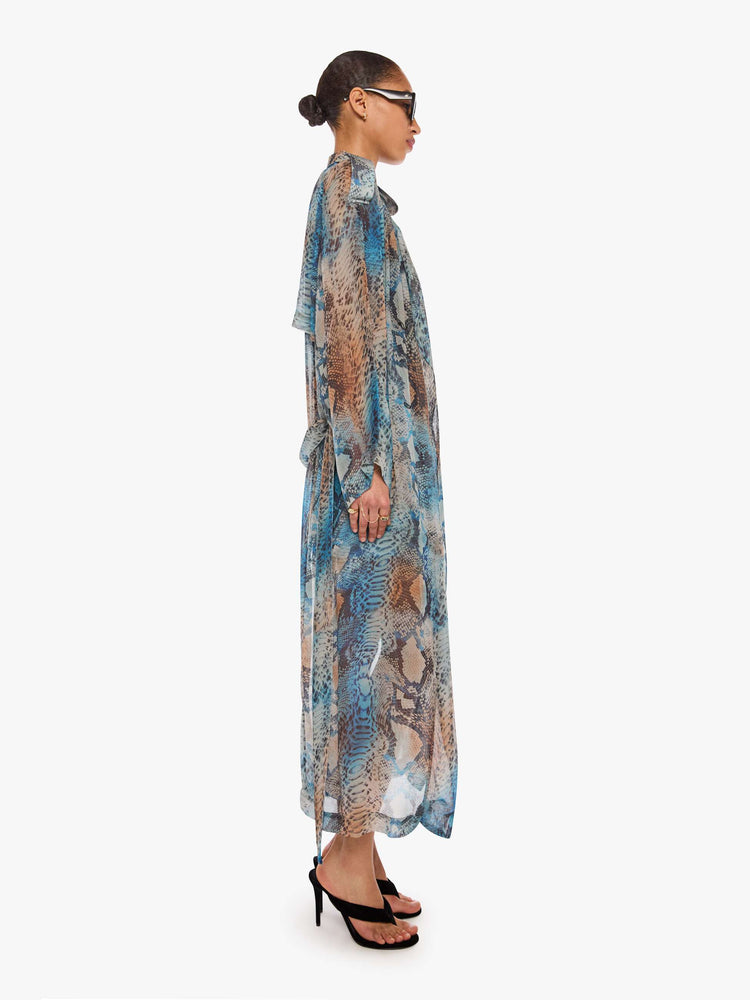 Side view of a woman in a blue, cream, brown and black oversized snake print jacket and features a notched collar, long sleeves and an ankle-length hem.