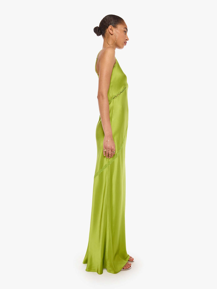 Side view of a woman in a silk chartreuse slip dress is designed with thin spaghetti straps, a V-neck, lace inset details, a floor-length hem and a loose, flowy fit.