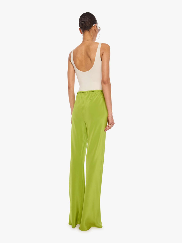 Back view of a woman in a green pant with an elastic waistband, a loose leg and an extra-long hem.