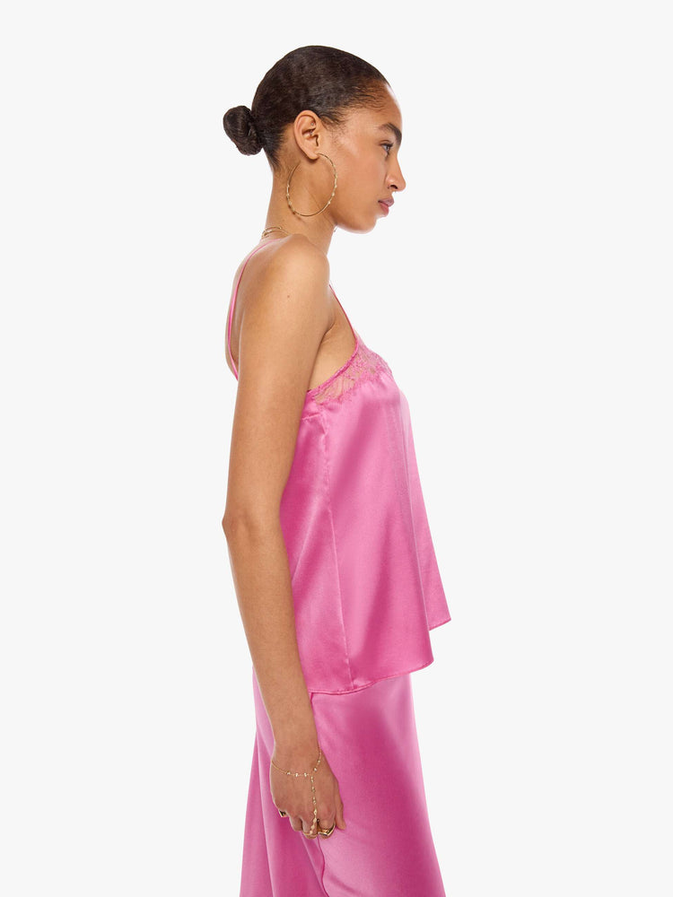 Side view of a woman in a pink cami with thin spaghetti straps, a lace-trimmed V-neck and a loose, flowy fit.