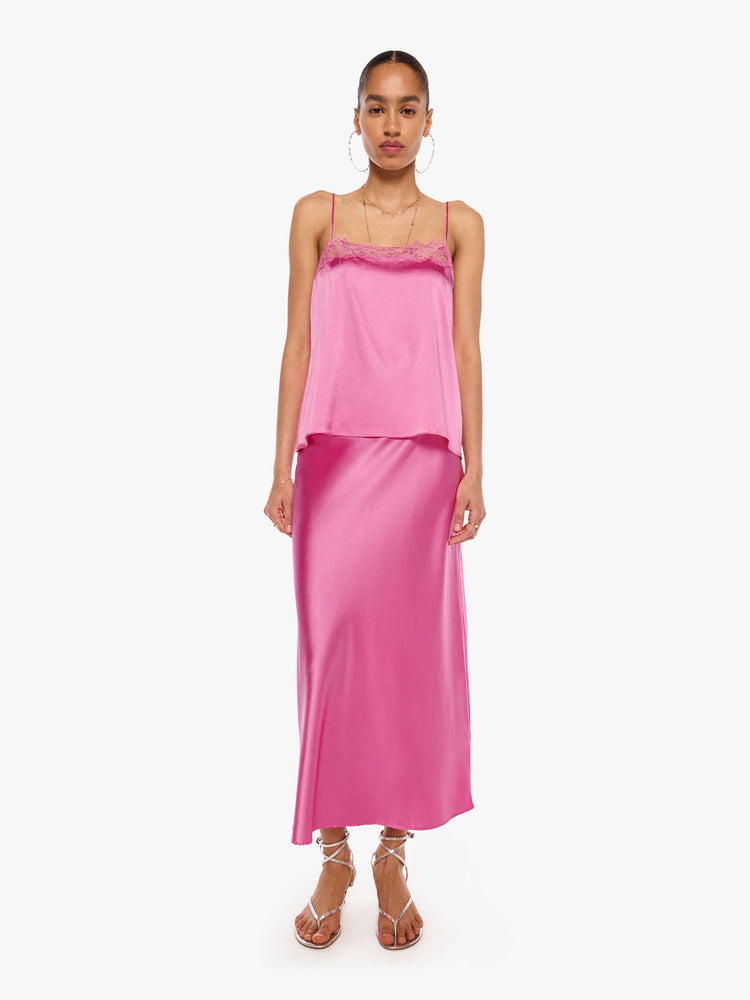 Full body view of a woman in a pink cami with thin spaghetti straps, a lace-trimmed V-neck and a loose, flowy fit.