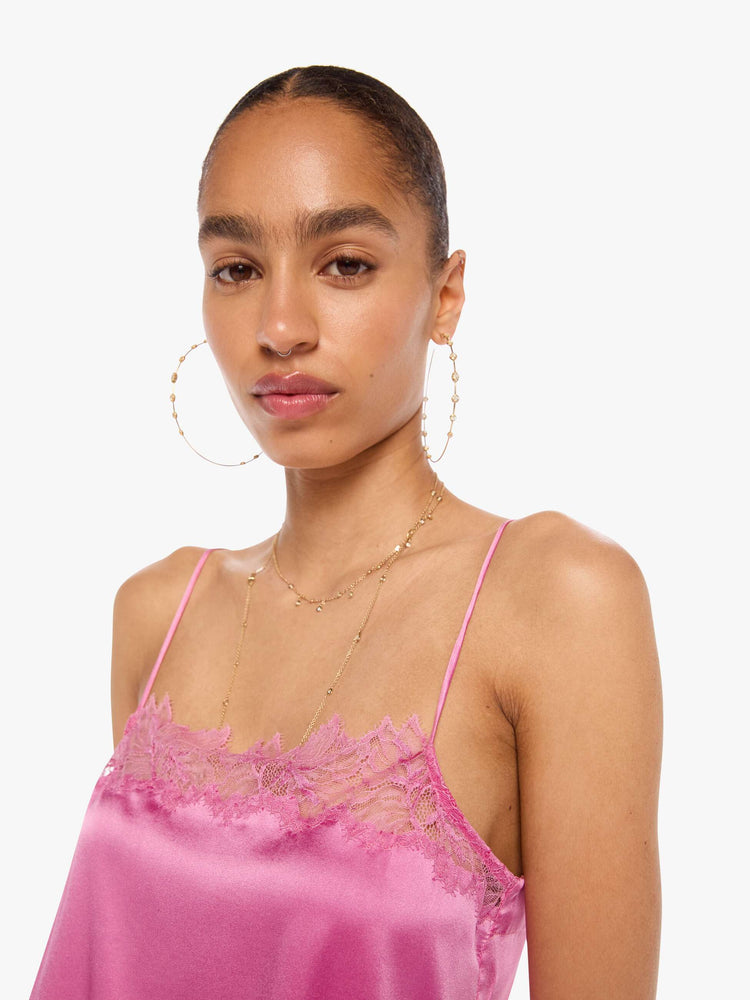 Close up view of a woman in a pink cami with thin spaghetti straps, a lace-trimmed V-neck and a loose, flowy fit.