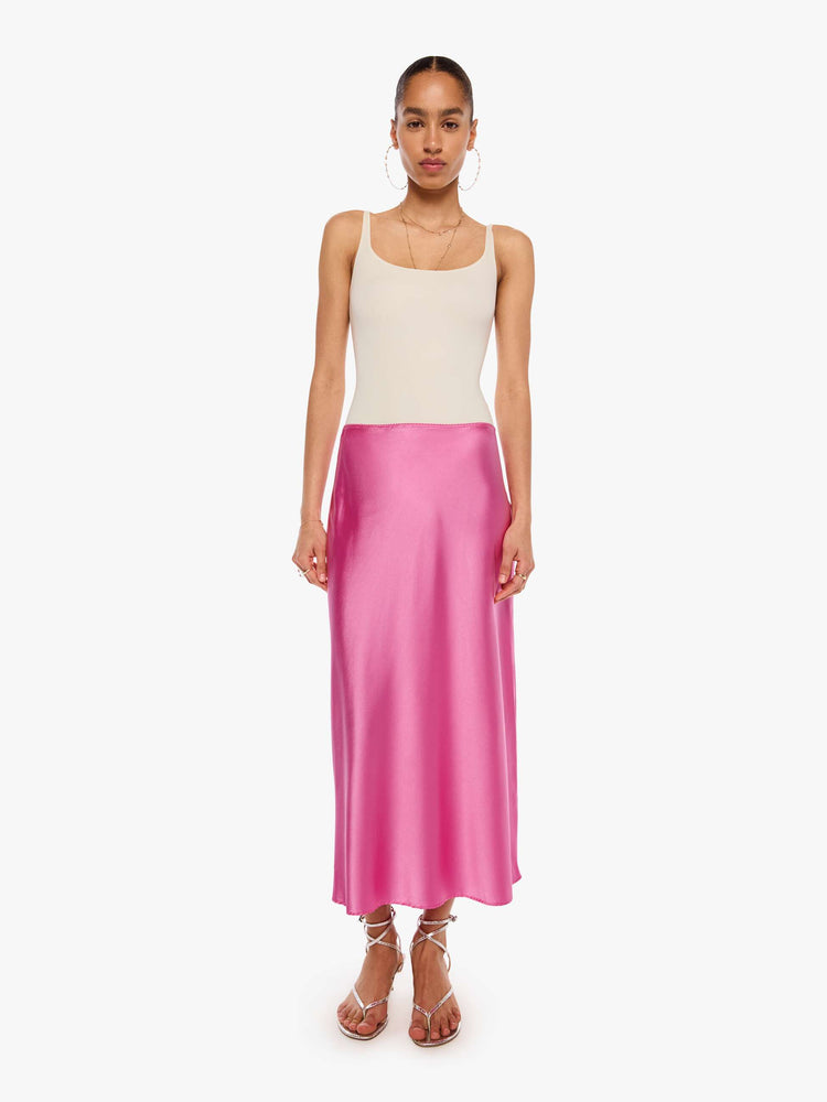 Front view of a woman in a pink bias-cut maxi skirt is designed with a straight fit and a flowy, ankle-grazing hem.