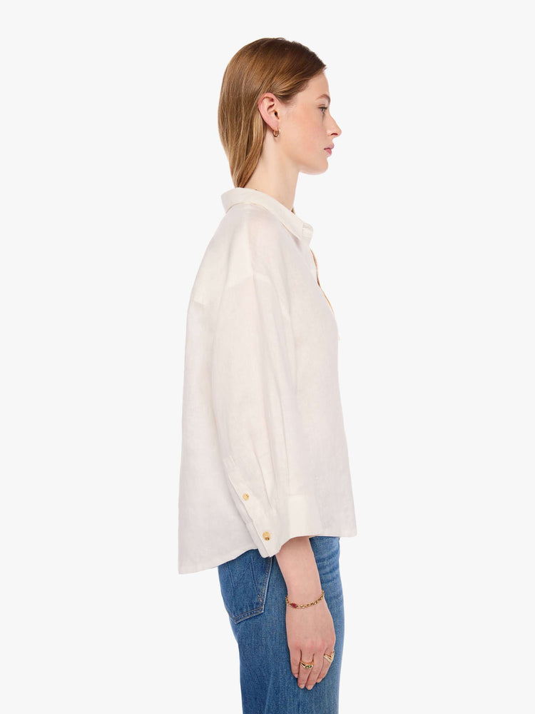 Side view of a woman in a shirt is a classic button-up with drop shoulders, cropped long sleeves and a patch pocket on the chest.