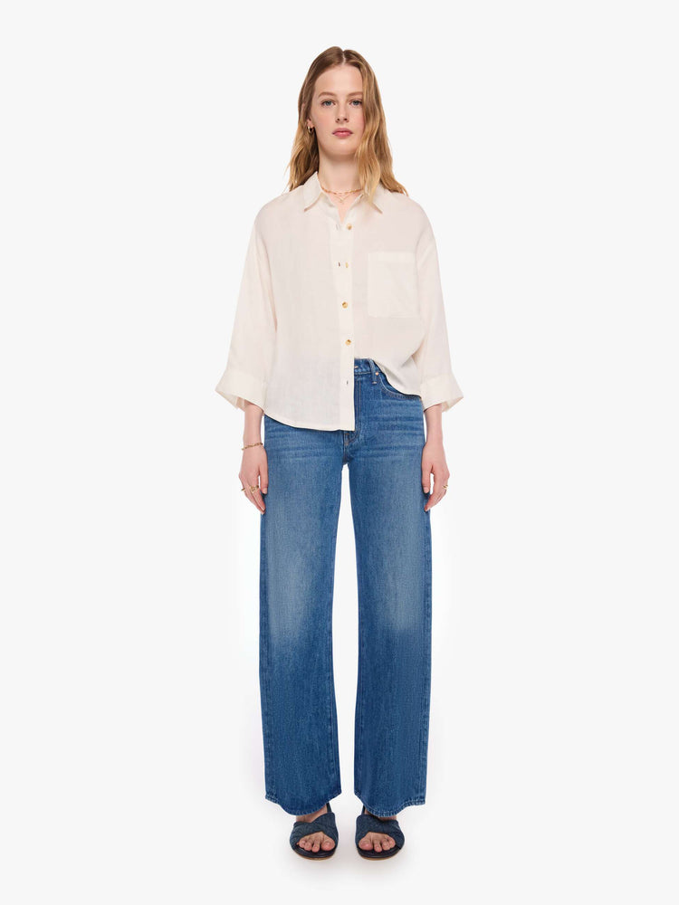 Full body view of a woman in a shirt is a classic button-up with drop shoulders, cropped long sleeves and a patch pocket on the chest.