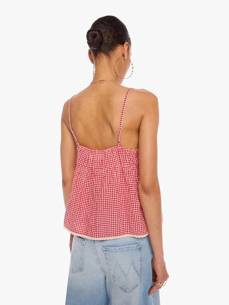 Back  view of a woman in a red and off-white gingham thin spaghetti straps, a V-neck, gathered bodice and buttons down the front.