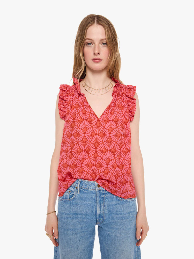 Front view of a woman in a vneck top pink and orange graphic print, and features short, ruffled sleeves and a boxy fit.