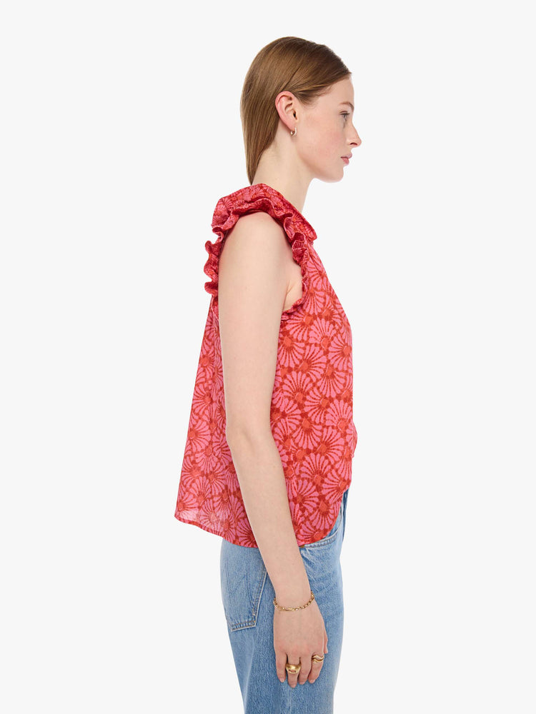 Side view of a woman in a vneck top pink and orange graphic print, and features short, ruffled sleeves and a boxy fit.