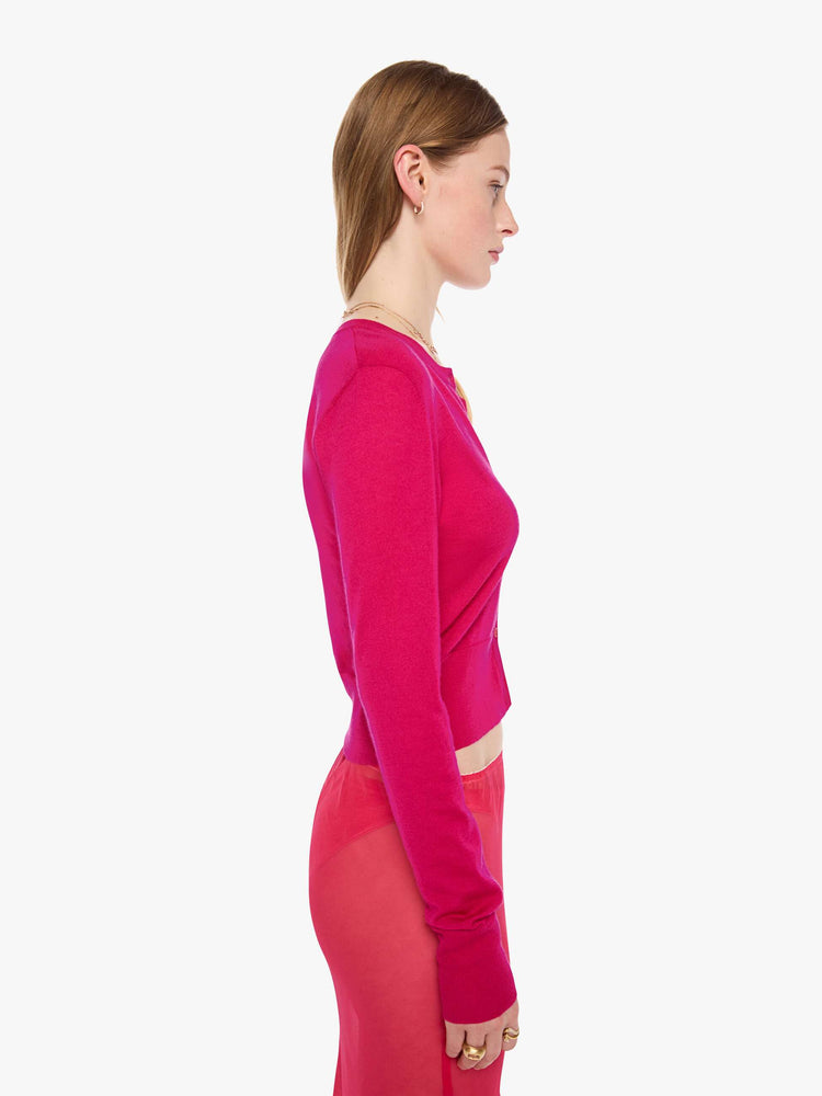 Side view of a woman in a hot pink cardigan from SPRWMN with a crewneck and a narrow fit.