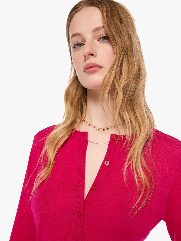 Close up view of a woman in a hot pink cardigan from SPRWMN with a crewneck and a narrow fit.