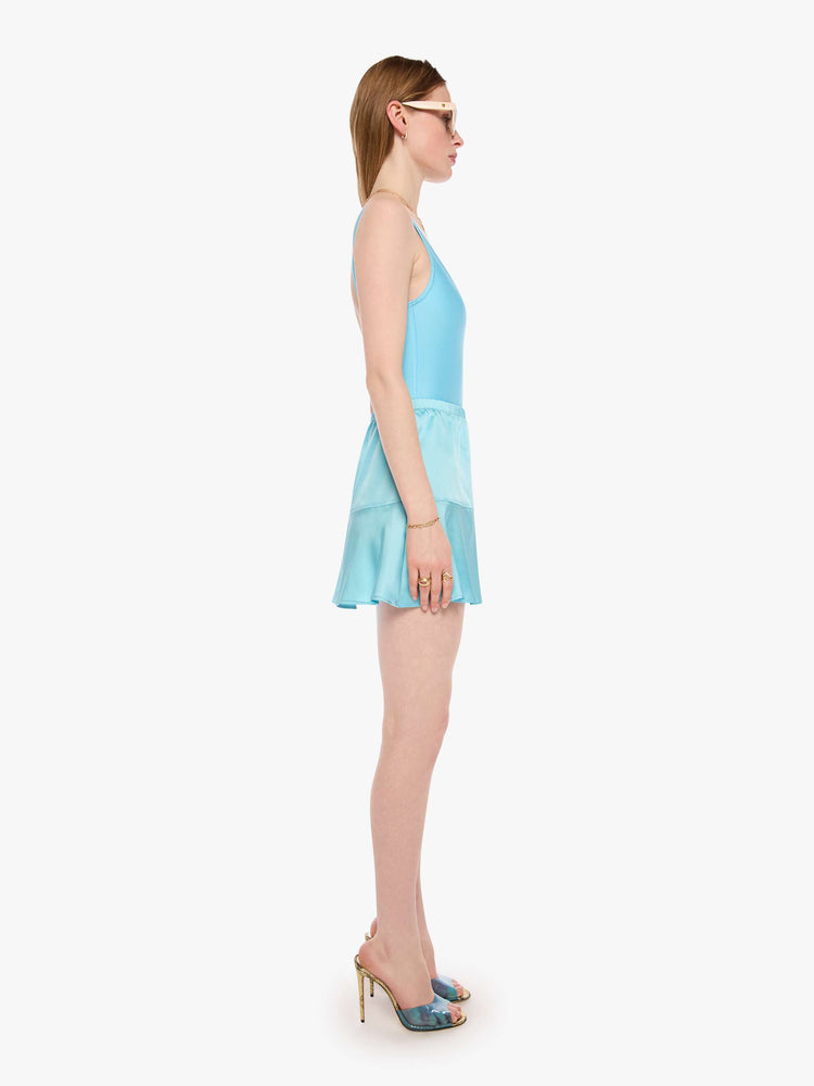 Side view of a woman in a baby blue mini skirt from SPRWMN with a high rise, thigh-grazing hem and a loose, flowy fit.