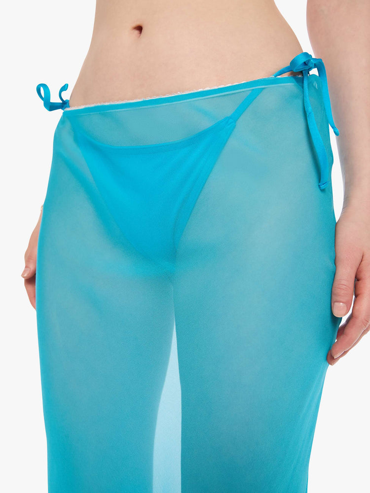 Close up view of a woman in a turquoise see-through maxi skirt from SPRWMN with an elastic waist, narrow fit and ankle-length hem. 