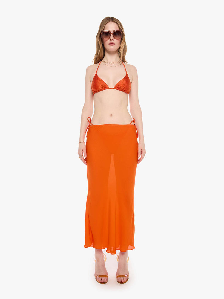 Full body  view of a woman in string bikini top from SPRWMN with decorative rhinestones throughout in orange, the bikini top has a triangle design and tie closures.