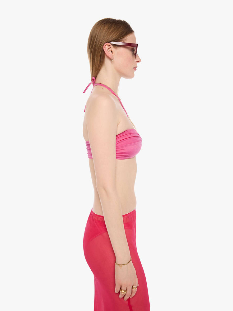 Side view of a woman in a pink bikini top from SPRWMN with an adjustable fit has a twisted bandeau design and removable straps.